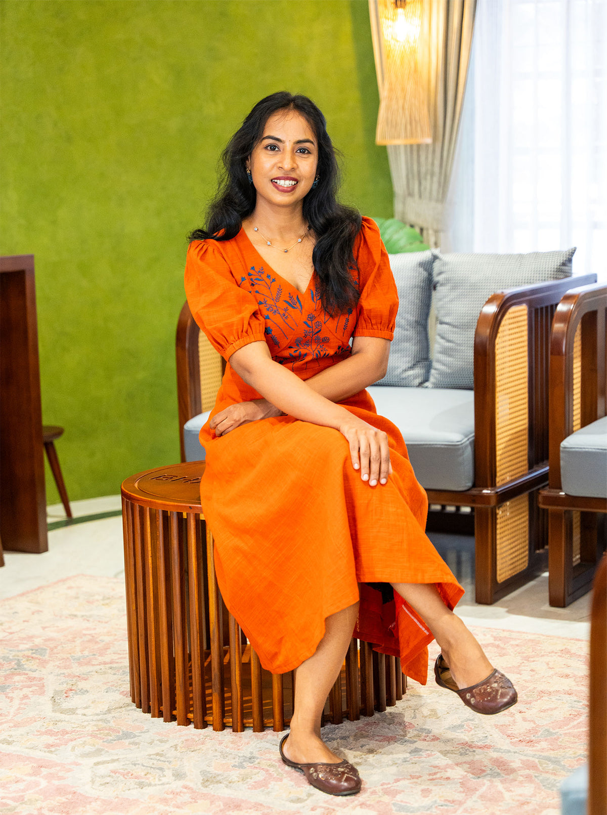 Seated in orange embroidered cotton dress showing comfortable everyday fit - Ariyaa