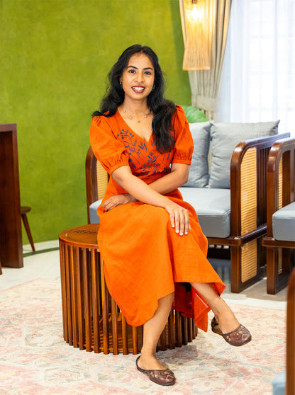 Seated in orange embroidered cotton dress showing comfortable everyday fit - Ariyaa