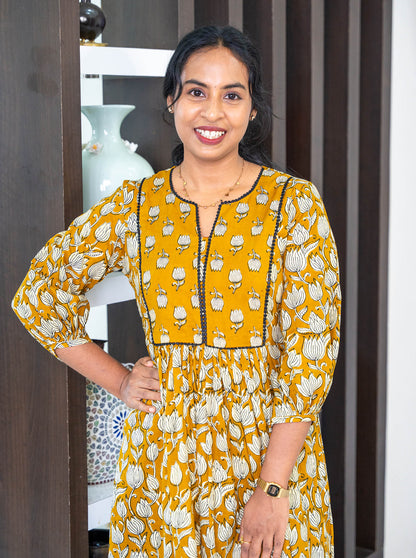 Close-up of tanned yellow floral motif cotton fabric texture - Ariyaa